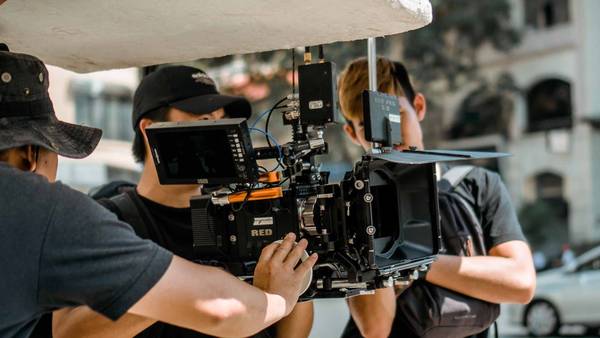 Two camera operators working a large film camera on an outdoor shoot.